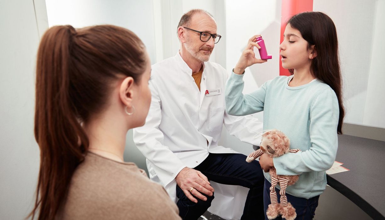 Kind, übt in der Apotheke, einen Inhalator zu benutzen.