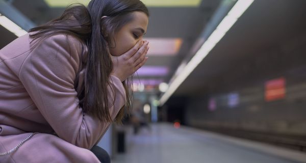 Frau, sitzt in einem Ubahn-Schacht und hat Angst.