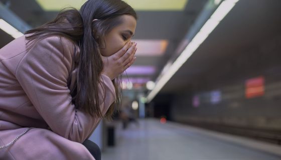 Frau, sitzt in einem Ubahn-Schacht und hat Angst.