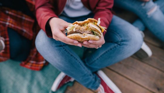 Jugendliche, hält einen Burger in der Hand.