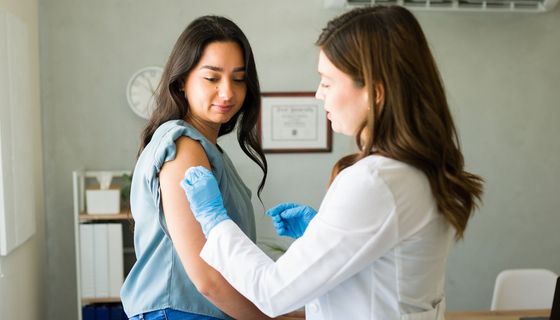 Ärztin bereitet Frau auf Grippeimpfung vor.