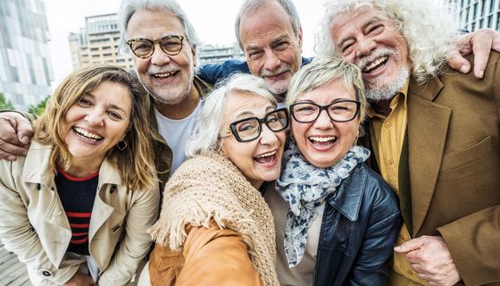 Eine Gruppe älterer Menschen macht ein Selfie und lacht.