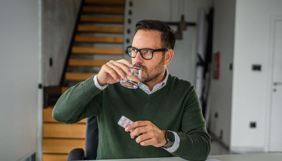 Mann nimmt eine Tablette ein.