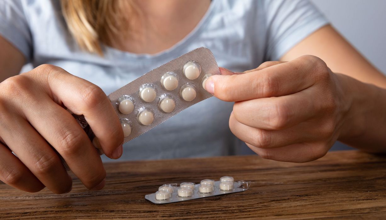 Frau mit zwei Tabletten-Packungen.