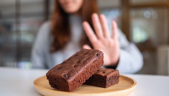 Frau, lehnt zwei Brownie-Stückchen ab.