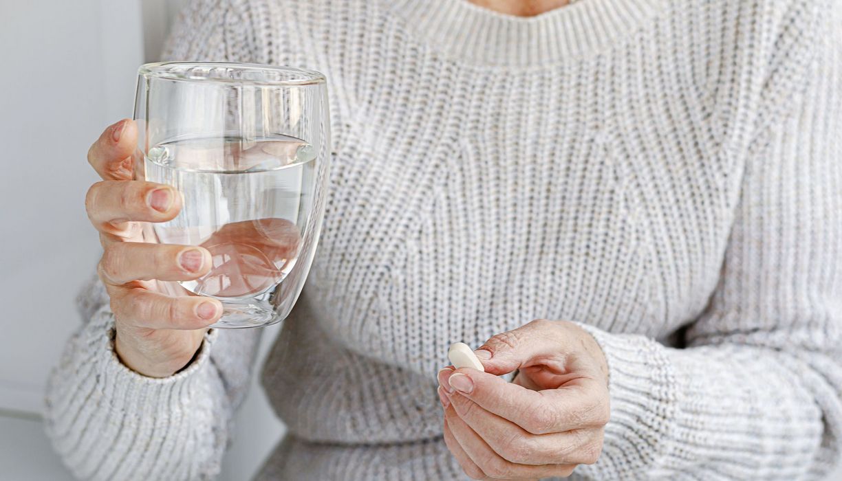 Frau, hält ein Glas Wasser in der Hand.