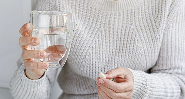 Frau, hält ein Glas Wasser in der Hand.