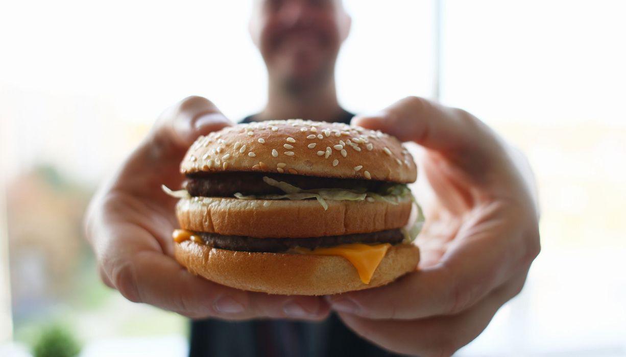 Mann, hält Hamburger in die Kamera.