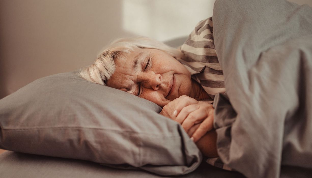 Frau, liegt im Bett und schläft.