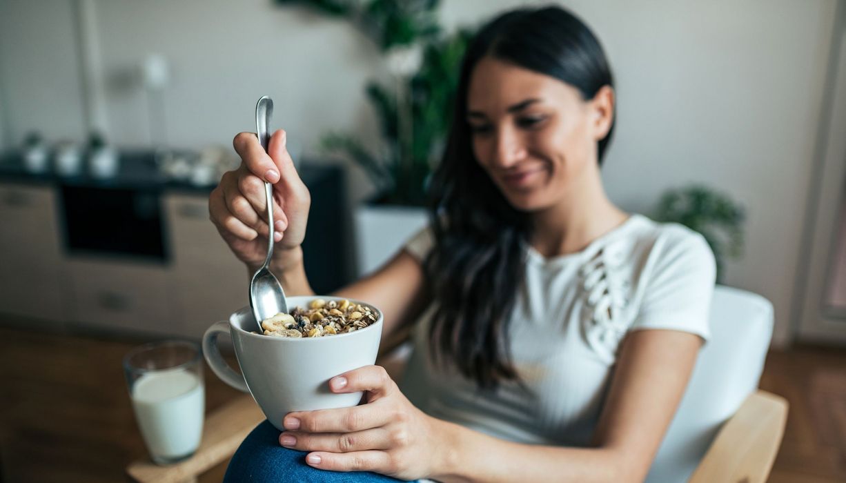 Junge Frau, isst ein Müsli.