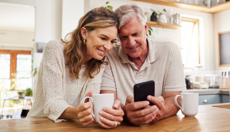 Älteres Paar schaut gemeinsam auf ein Smartphone.