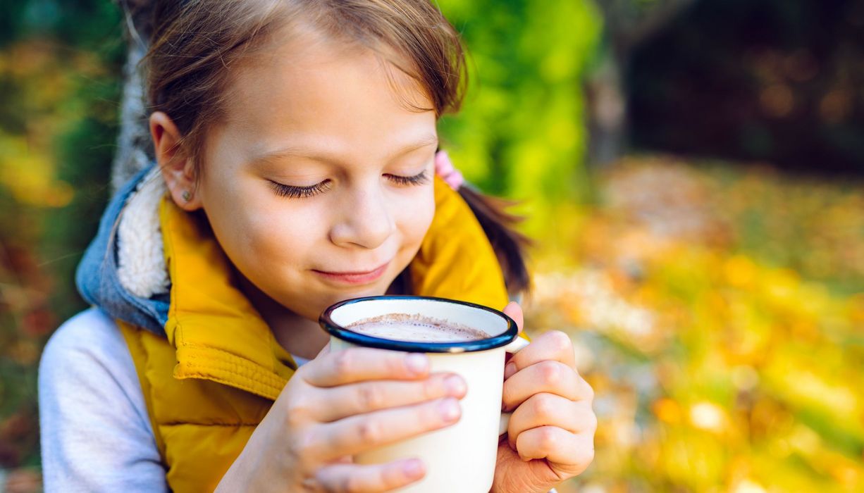 Junges Mädchen trinkt eine Tasse Kakao.