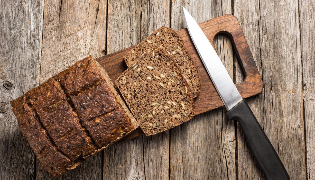 Vollkornbrot auf Holzbrett mit Messer.