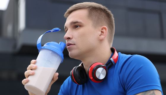 Junger Mann trinkt aus einer halbtransparenten Flasche, darin eine dickflüssige Füssigkeit.