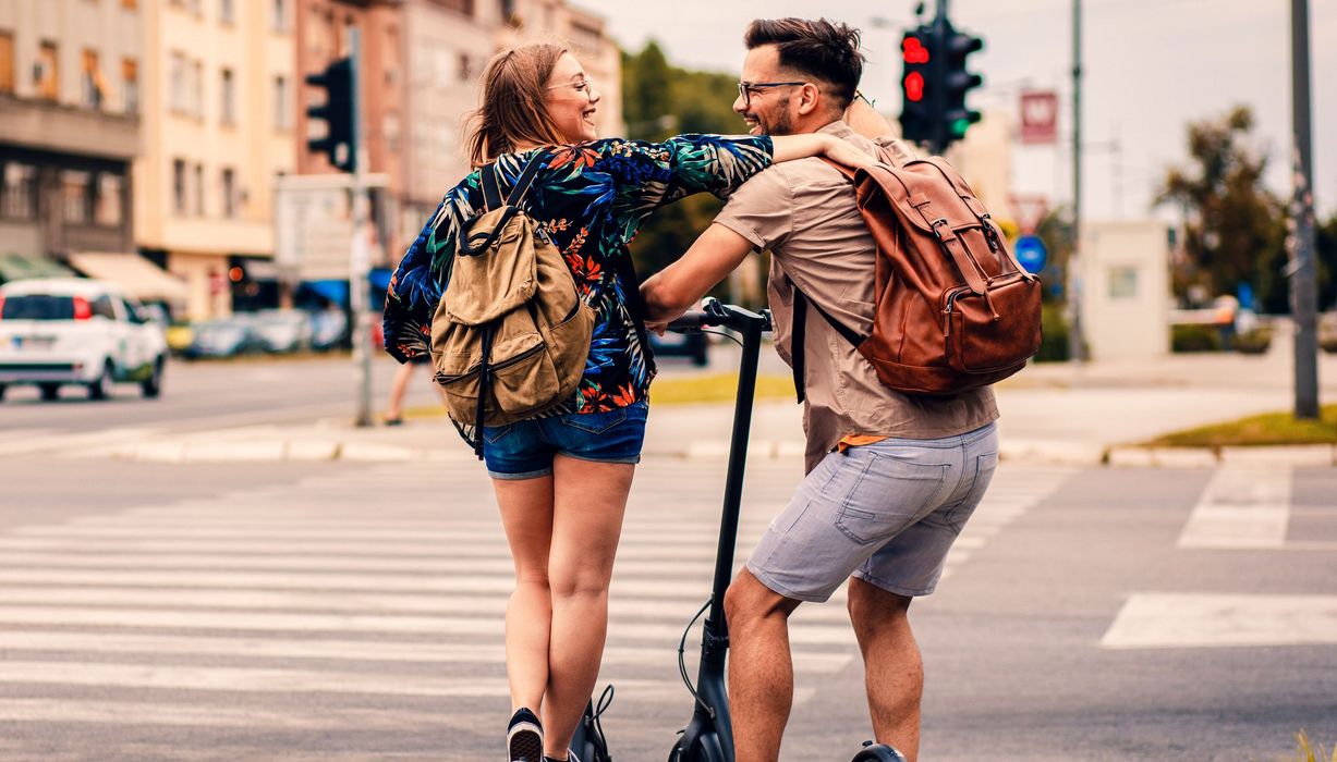 Ein junges Pärchen, fährt mit E-Rollern durch die Stadt.