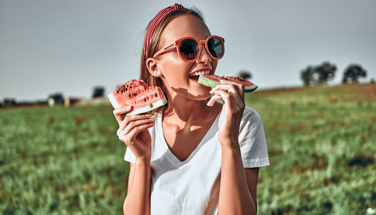 Junge Frau, beißt von einer Wassermelone ab.