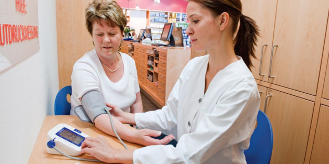 Junge Apothekerin misst den Blutdruck einer Patientin.