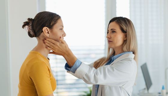 Ärztin tastet die Halslymphknoten bei einer Patientin ab.