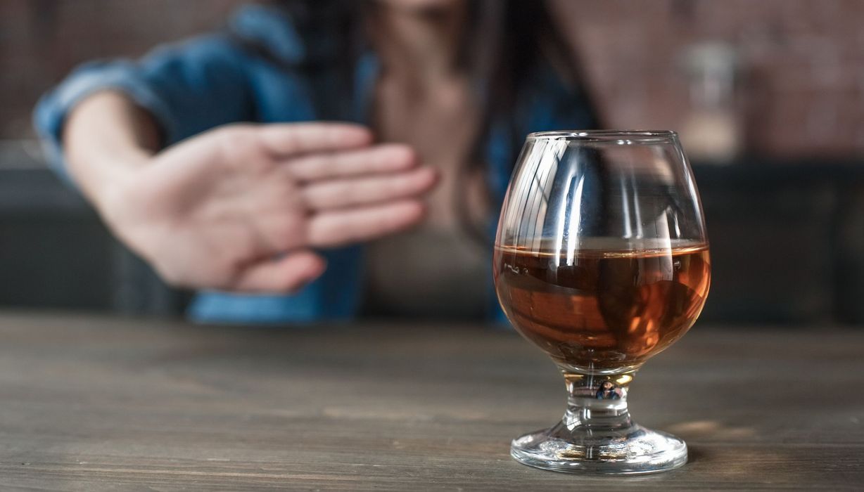 Frau, lehnt ein Glas Alkohol ab.