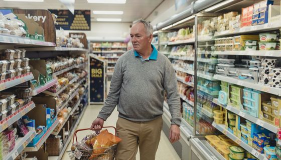 Älterer Mann mit Einkaufskorb im Supermarkt