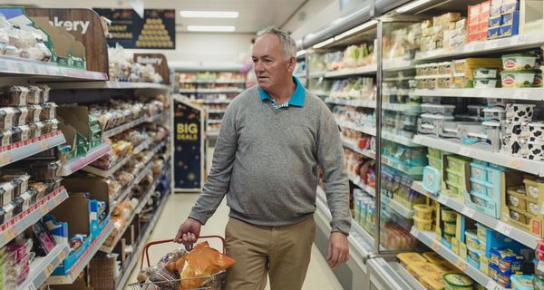 Älterer Mann mit Einkaufskorb im Supermarkt