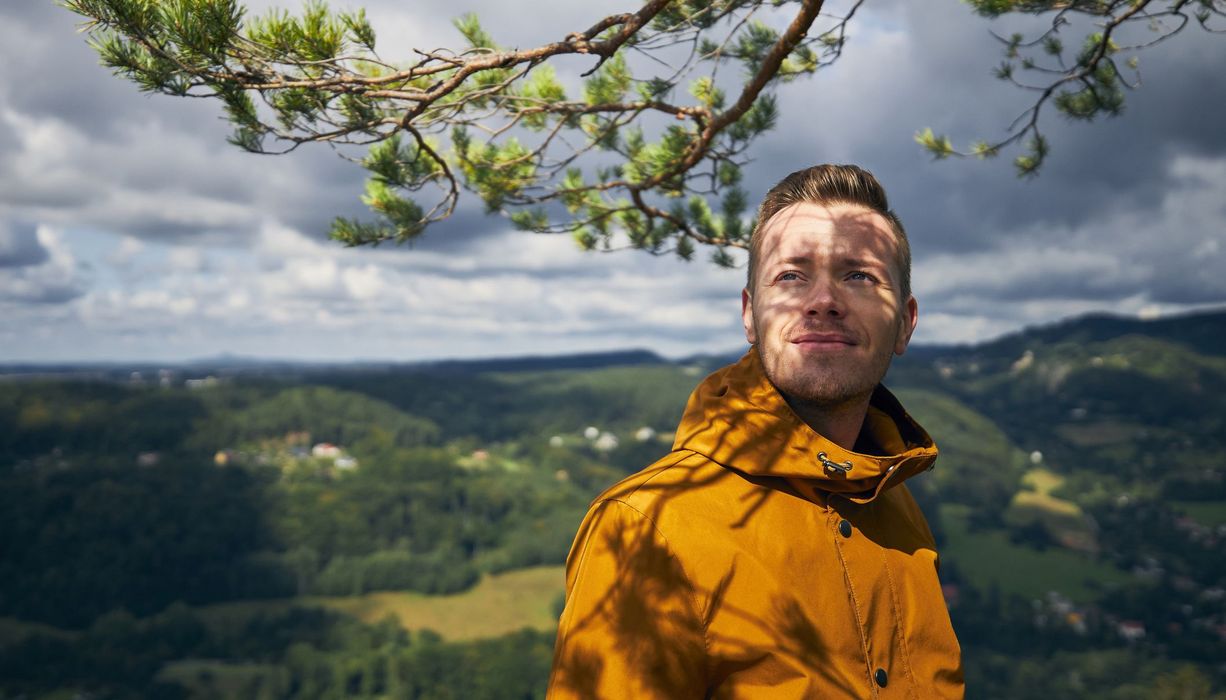 Mann in Regenkleidung, vor bewölktem Himmel.