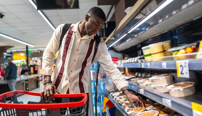 Mann im Supermarkt, schaut sich Fertiggerichte an.