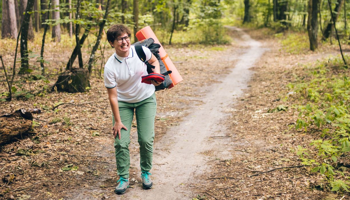 Frau, die im Wald wandert, hält sich das Knie.