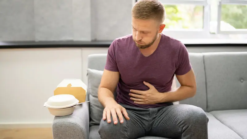 Mann hält sich den Bauch nach üppigem Essen.