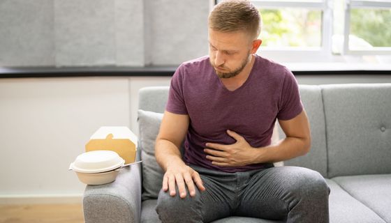 Mann hält sich den Bauch nach üppigem Essen.