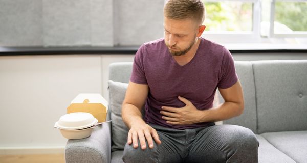 Mann hält sich den Bauch nach üppigem Essen.