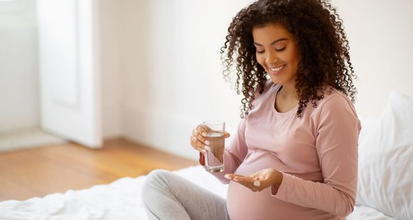 Schwangere Frau nimmt eine Tablette.