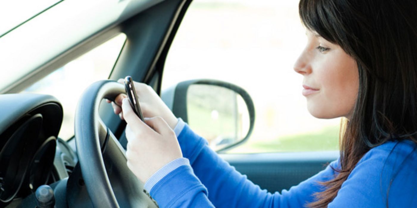 Frau bedient während der Fahrt ihr Handy.