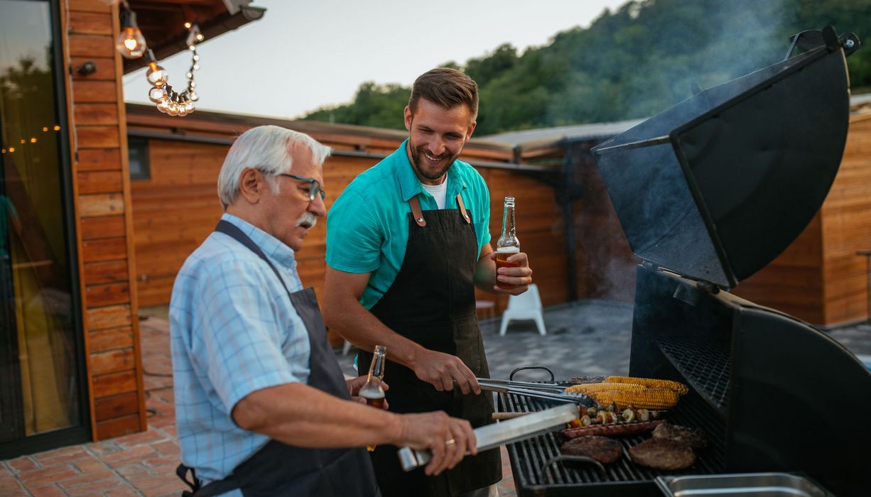 Älterer Mann, grillt zusammen mit seinem Sohn.