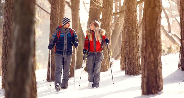 Junges Paar beim Nordic Walking im verschneiten Wald.