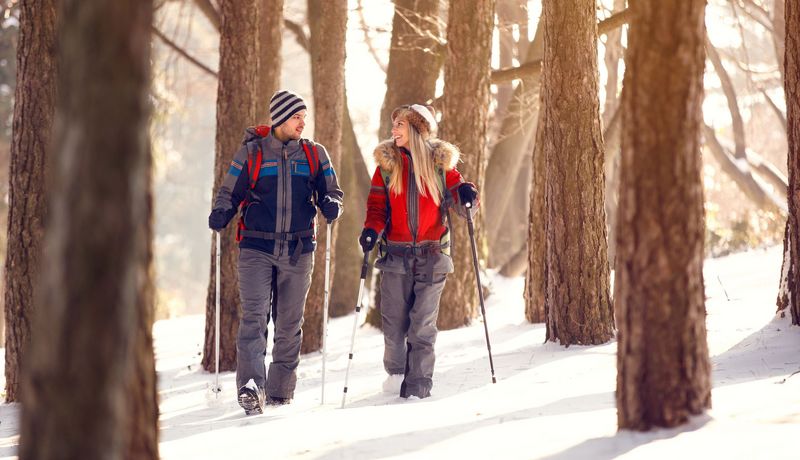 Junges Paar beim Nordic Walking im verschneiten Wald.