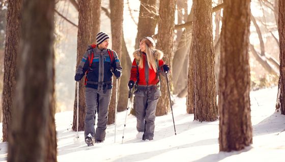 Junges Paar beim Nordic Walking im verschneiten Wald.