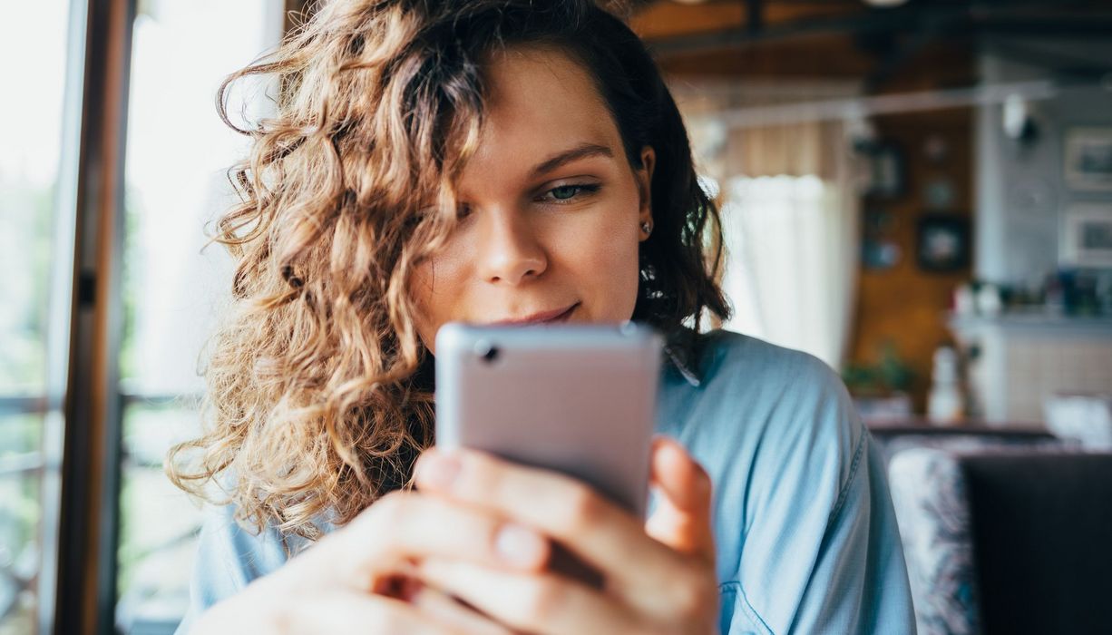 Junge Frau, tippt auf ihrem Smartphone.