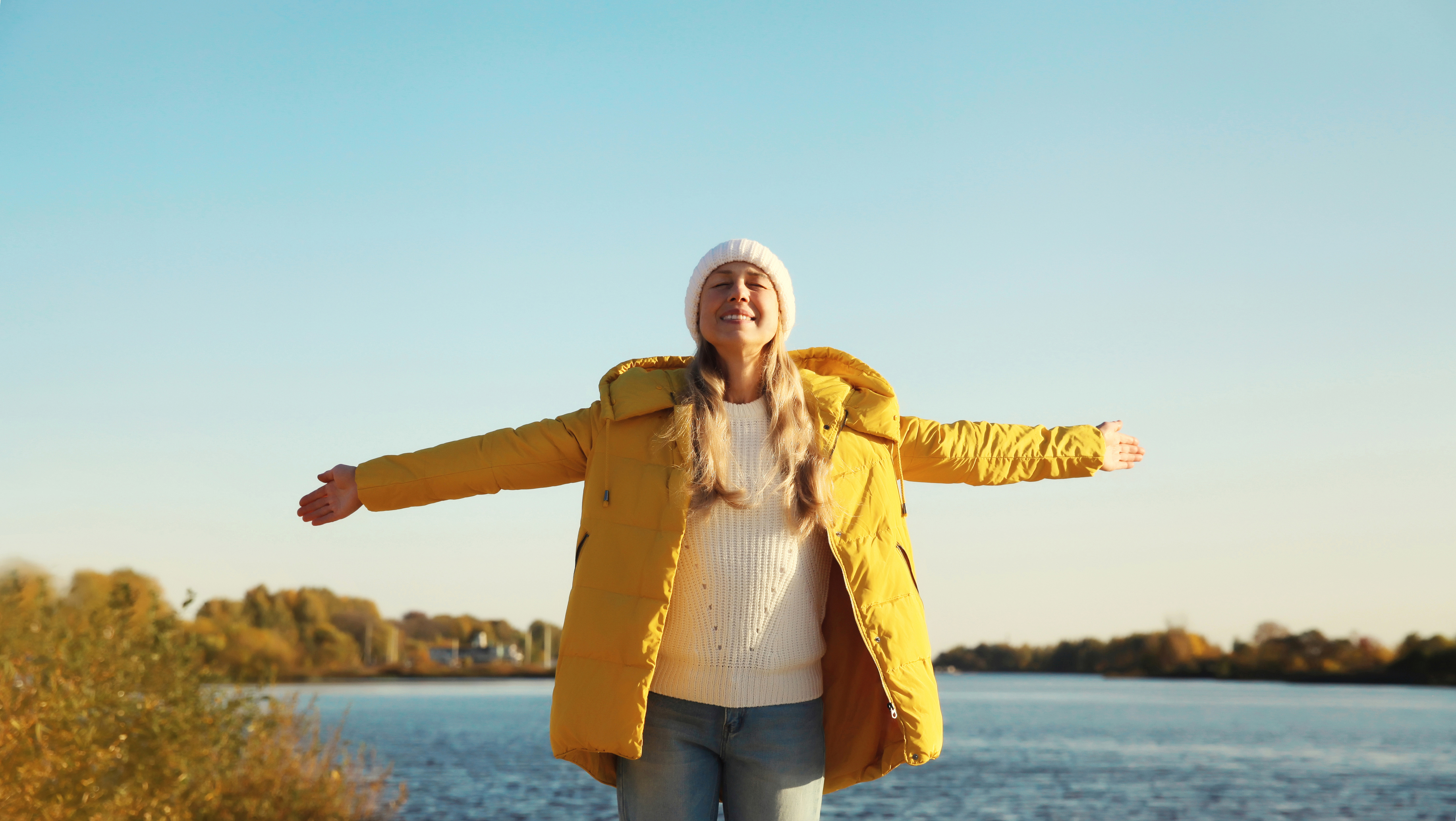 Frau mit gelber Daunenjacke in der Sonne