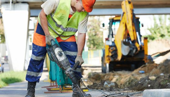 Junger Bauarbeiter entfernt Asphalt.
