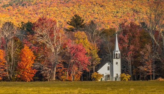 Kirche vor herbstlich gefärbtem Wald