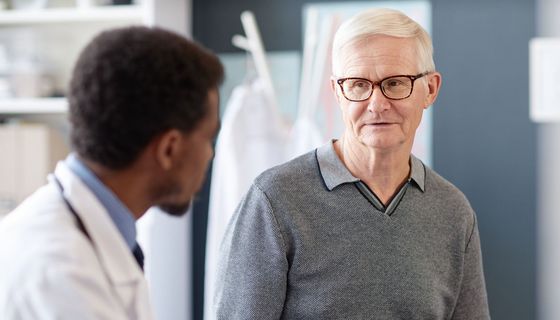 Älterer Herr sitzt bei einem Arzt, der mit notiert.