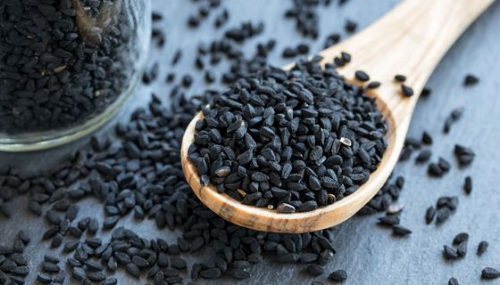 Holzlöffel, auf dem ein Haufen Schwarzkümmelsamen liegt.