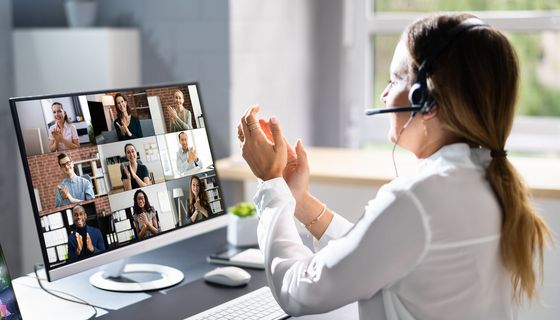 Frau mit Headset in einem Online-Meeting: Alle applaudieren.