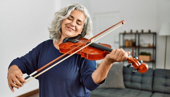 Grauhaarige Frau spielt Violine.