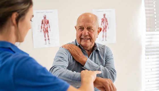 Mann mit schmerzender Schulter bei einer Ärztin.