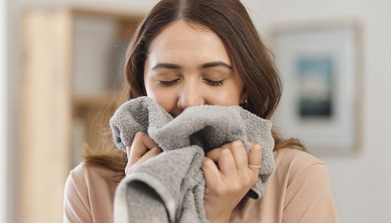 Frau riecht an einem Handtuch.