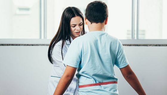 Ärztin misst Bauchumfang eines leicht übergewichtigen Kindes