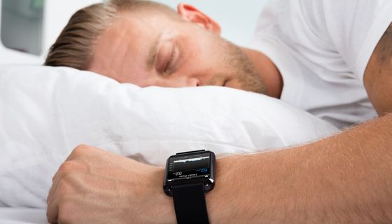 Ein Mann schläaft mit einer Smartwatch am Handgelenk.