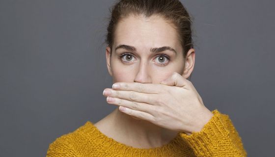 Frau hält sich eine Hand vor den Mund.